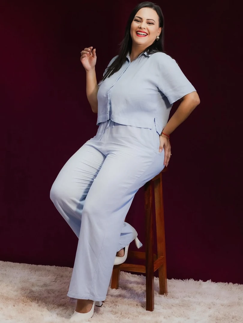 Camila Araújo sorrindo, sentada em um banco